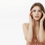 woman having headache during periods feeling frustrated concerned touching temples frowning from discomfort suffering from painful feeling migraine standing concerned 1 1